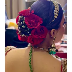 A side view of a classic red rose bridal bun, showing how the matha patti is elegantly incorporated.