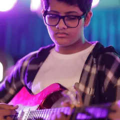 A close-up of one of our talented guitarists, completely absorbed in the music during his live performance. Our program helps students develop the focus needed for stage performances.