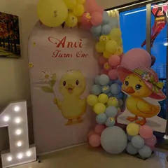An adorable duckling theme for Anvi's first birthday. This decoration includes a custom printed backdrop, a life-sized duckling cutout, and a pastel balloon arch.