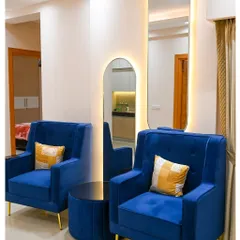 A pop of color can transform a room. These royal blue armchairs with gold-finished legs add a touch of contemporary chic, perfectly complemented by the backlit arched mirror that enhances the room's depth.