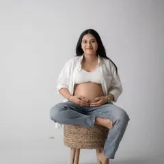 A modern and casual studio look, with the mom-to-be showing off her bare bump in jeans and an open white shirt. This style is relaxed and beautiful.