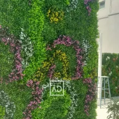 You can add color and patterns to your green wall. This custom vertical garden features swirls of artificial purple, yellow, and white flowers woven into the green foliage for a more decorative and vibrant look.