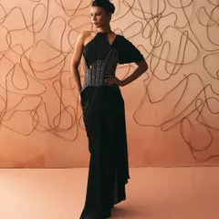 I believe clothes should hold the memory of nights that stretch past midnight. This pre-dstitched sari gown is my interpretation of that feeling, with a sculpted, hand-embroidered corset that anchors the fluid black drape. It is a balance of sharp structure and effortless elegance.