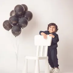 A stylish portrait with a simple chair and balloons. This minimalist setup keeps the focus on his adorable personality.