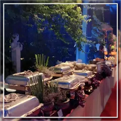 An atmospheric shot of a buffet line at an evening event. The combination of elegant silver chafing dishes and dramatic lighting creates a luxurious ambiance for your corporate dinners.