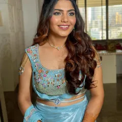 The waves are styled to frame the face beautifully, highlighting the client's features. This is a popular choice for sangeet and cocktail party hair.