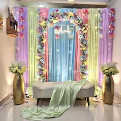 The full view of our pastel Mehendi setup, showcasing the multi-colored drapes, floral arch, and hanging umbrella tassels for a whimsical touch.