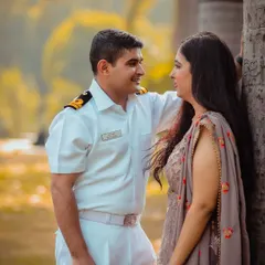 This is another beautiful shot from the couple's pre-wedding session, showcasing the groom's summer uniform. The warm, golden hour light and natural park setting create a soft and romantic atmosphere, perfect for capturing these quiet, shared glances.