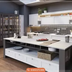 This design showcases a spacious, open-plan kitchen with a large central island providing ample workspace and storage. The contrast between the dark grey island and pantry unit with the clean white cabinetry adds visual depth and modern appeal.