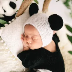 A close-up of our baby panda. The knitted panda hat and soft textures make this an incredibly cute and memorable shot, focusing on the baby's peaceful, sleeping face.
