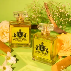 This bright and fresh composition for a floral and woody perfume uses a vibrant green background, yellow roses, and sandalwood sticks. The lighting and props are chosen to visually represent the fragrance notes of the scent.