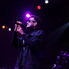 A singer caught in a moment of reflection between verses, bathed in soft purple light. These are the subtle emotional shifts I aim to capture during a set.