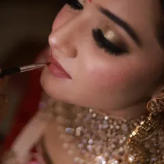 The final touch on a bridal look. This close-up shows the precise application of lipstick, a key step in creating a defined and long-lasting pout for the wedding day.
