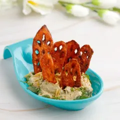 A signature fusion creation. Our Peri Peri Crispy Lotus Stem Chaat combines the unique crunch of lotus root with a zesty peri peri seasoning and creamy dip, served in a stylish spoon for an elegant bite.