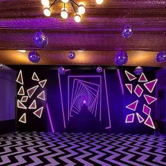 For a company party that needs to feel modern and energetic, I use bold design elements like this geometric neon light installation. Paired with a custom dance floor and hanging disco balls, this setup transforms any venue into a vibrant, unforgettable party zone.