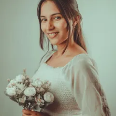 A sweet and simple indoor portrait with a soft, vintage feel. The model holding a bouquet of flowers adds a touch of innocence and charm to this gentle lifestyle shot.
