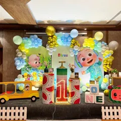 Here is a vibrant Cocomelon themed first birthday party. The setup includes large character cutouts, a custom backdrop, themed pedestals, and a light-up number '1' to bring the popular show to life.
