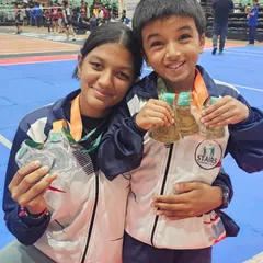 Two of our young athletes proudly displaying their medals from the Stairs National Games. Their smiles represent the joy of achieving their goals.
