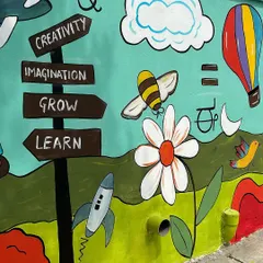 A close-up of the Montessori school mural, featuring a signpost with words like 'Creativity', 'Imagination', 'Grow', and 'Learn'. The design is meant to be both fun and educational.