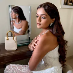 A side profile showcasing the soft glam makeup and delicate pearl hair accessories for this wedding guest.