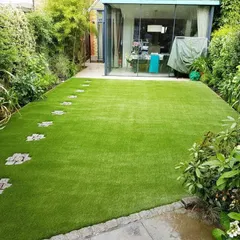 I integrated cobblestone stepping stones into this artificial lawn, creating a charming pathway that leads to the house. This shows how you can blend functional paths with the beauty of a perfect green lawn.