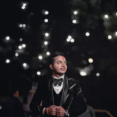An outdoor groom portrait at night, with bokeh lights in the background. This creates a magical and celebratory atmosphere, perfect for capturing the groom's style during an evening event.
