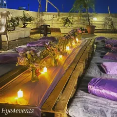 This lavender-themed low-seating setup was designed for a teen's birthday party on a terrace. We used purple cushions and floral arrangements, with candlelight creating a beautiful glow against the evening sky.