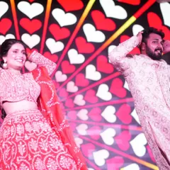A fun, candid moment during a couple's performance against a backdrop of hearts. My choreography always includes moments for you to be yourselves and just enjoy dancing together.