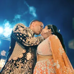 A passionate kiss under the stars, a perfect silhouette against the dramatic lighting of the Sangeet night. This is love in its most cinematic form.