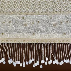 A close-up of the saree's pallu, featuring a dense chevron pattern and floral motifs, all highlighted with mirrorwork and finished with hand-sewn tassels.