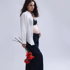 A striking and editorial-style portrait. The simple white shirt, dark trousers, and bold red flowers create a modern, artistic image that is both strong and feminine.