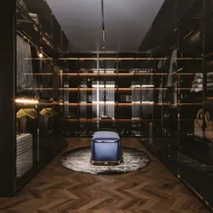 A high-end, moody walk-in closet with dark wood, smoked glass doors, and warm backlighting. This design exudes sophistication and creates a dramatic, gallery-like space for your wardrobe.