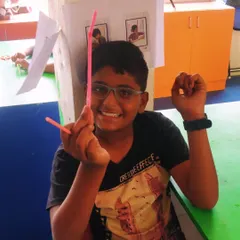 A smiling student shows off the simple helicopter toy he made using straws, a fun project that demonstrates the principles of lift.