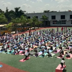An aerial view of our students practicing yoga on the school grounds, with our school buses in the background, showcasing our campus facilities.