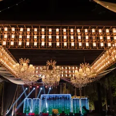 A spectacular sangeet lighting setup combining a massive, custom-built rectangular chandelier with classic crystal chandeliers over the stage. This is how I layer lighting to create depth and drama.