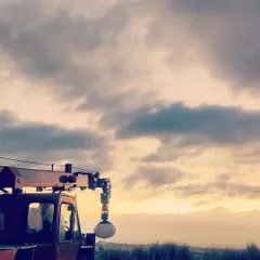 A shot from a film set, showing a crane with a light set up against a sunset sky. This gives a glimpse into the scale of production and lighting setups I work with.