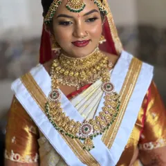 This is the traditional South Indian 'Goddess' look that I love creating for the Muhurtham. For Harshitha, we went with bold, 3D eyes and a classic red lip to complement her stunning gold jewelry and white Kanjivaram saree.