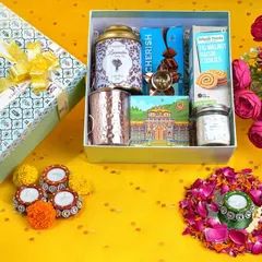 A top-down creative shot of a gift hamper, styled with flowers and diyas on a bright yellow background. This vibrant flat lay is designed to grab attention on social media.