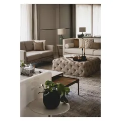 A tufted ottoman serves as a soft, central coffee table, inviting you to put your feet up. The layering of neutral fabrics and textures creates a sophisticated yet cozy atmosphere.