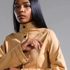 A close-up on a structured fashion look, where the makeup is kept neutral and glowing to complement the high-neck jacket. The hair is styled straight and sleek to maintain a sharp silhouette.