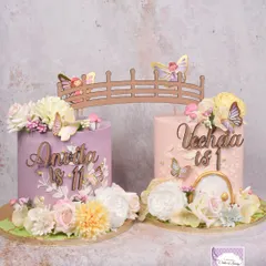 The two stunning centerpiece cakes for the Fairy Garden party, connected by a wooden bridge topper.