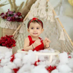 A happy smile that shows the beauty of simplicity. The red outfit pops against the neutral, textured backdrop.