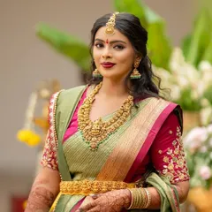The perfect portrait of a Kalasthree bride. She wears a beautiful sage green Kanjeevaram with a contrasting pink border, complemented by a hand-embroidered pink blouse.