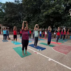 A large group of students stretching together during an outdoor class. Practicing in nature adds a unique element of peace and connection to the experience.