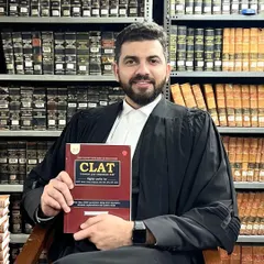 A professional portrait of me in a law library holding my CLAT book. This guide is a product of my experience as both a practicing advocate and a mentor who understands the challenges of law entrance exam preparation.