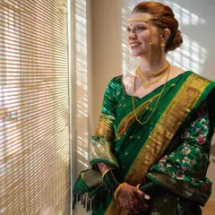 A portrait of the bride looking out the window, dressed in full Marathi bridal attire. The traditional jewelry, including the nath (nose pin) and mundavlya, completes her stunning transformation.