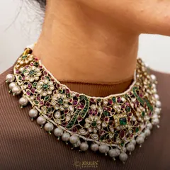 A luxe legacy in a single piece. This intricate choker is a masterpiece of craftsmanship, with floral motifs in polki, emeralds, and rubies creating a rich tapestry of color and sparkle.