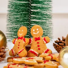 A pair of our festive gingerbread men cookies, standing in a winter wonderland scene.