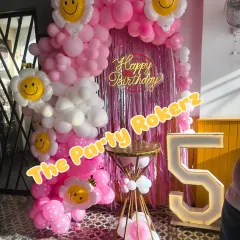 A sweet and happy flower and smiley-themed 5th birthday. The pink and white balloon arch is decorated with large smiley-face flower balloons, creating a cheerful atmosphere.
