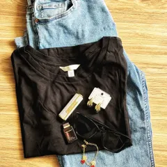 A flat lay of my daily essentials. A classic black t-shirt and jeans are elevated with carefully chosen accessories: a signature perfume, stylish sunglasses, and delicate gold jewelry.
